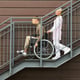 Side view of smiling friendly female rehabilitation centre worker pushing wheelchair with patient wh
