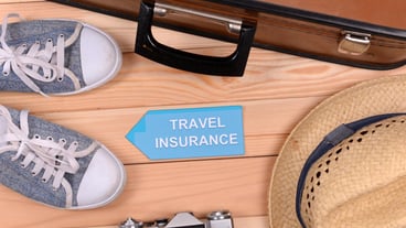 Suitcases and tourist articles with travel insurance on wooden background
