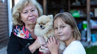 Woman and girl hug dog in yard