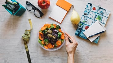 Crop hand mixing salad in office