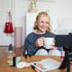Portrait of a sweet smiling woman, a blonde girl drinking tea and recording a casual lifestyle video blog.