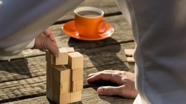 Man building a complete construction from wooden toy blocks