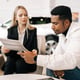 Medium shot of female manager consulting doubtful black buyer giving purchase agreement for review