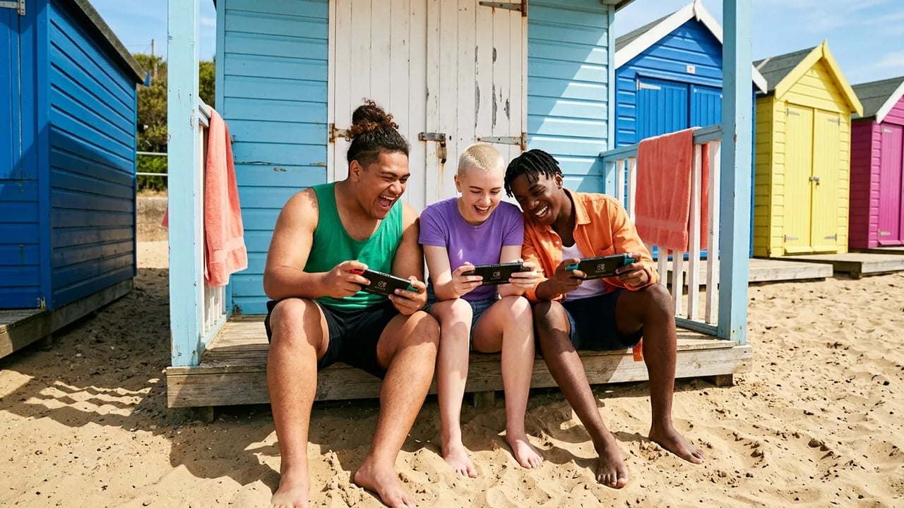 Three friends laughing while sitting on the porch of a colorful beach hut, each holding and playing on a Nintendo Switch console.