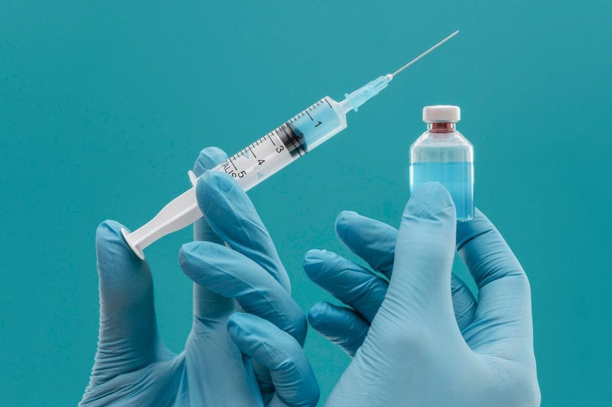 vaccine-bottle-and-syringe-held-by-doctor-with-gloves-jpg