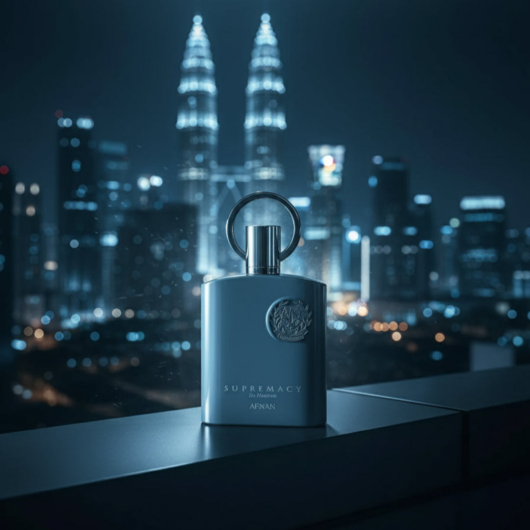 Supremacy In Heaven perfume shot on rooftop ledge overlooking Kuala Lumpur skyline, blue night lights, bokeh towers, masculine cinematic mood, cool wind effect.