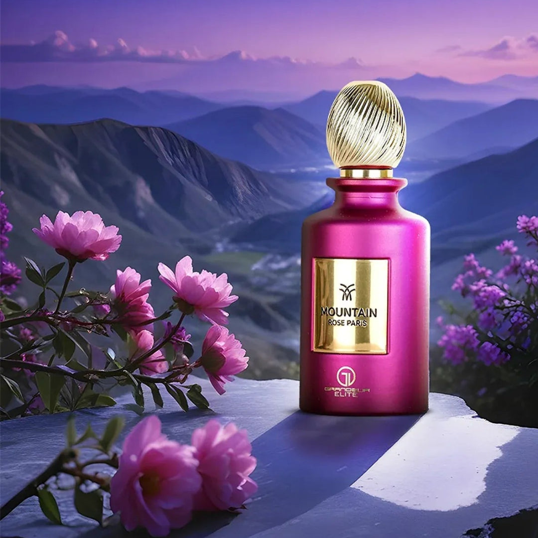 Pink perfume bottle with gold cap on a mountain landscape with pink flowers.
