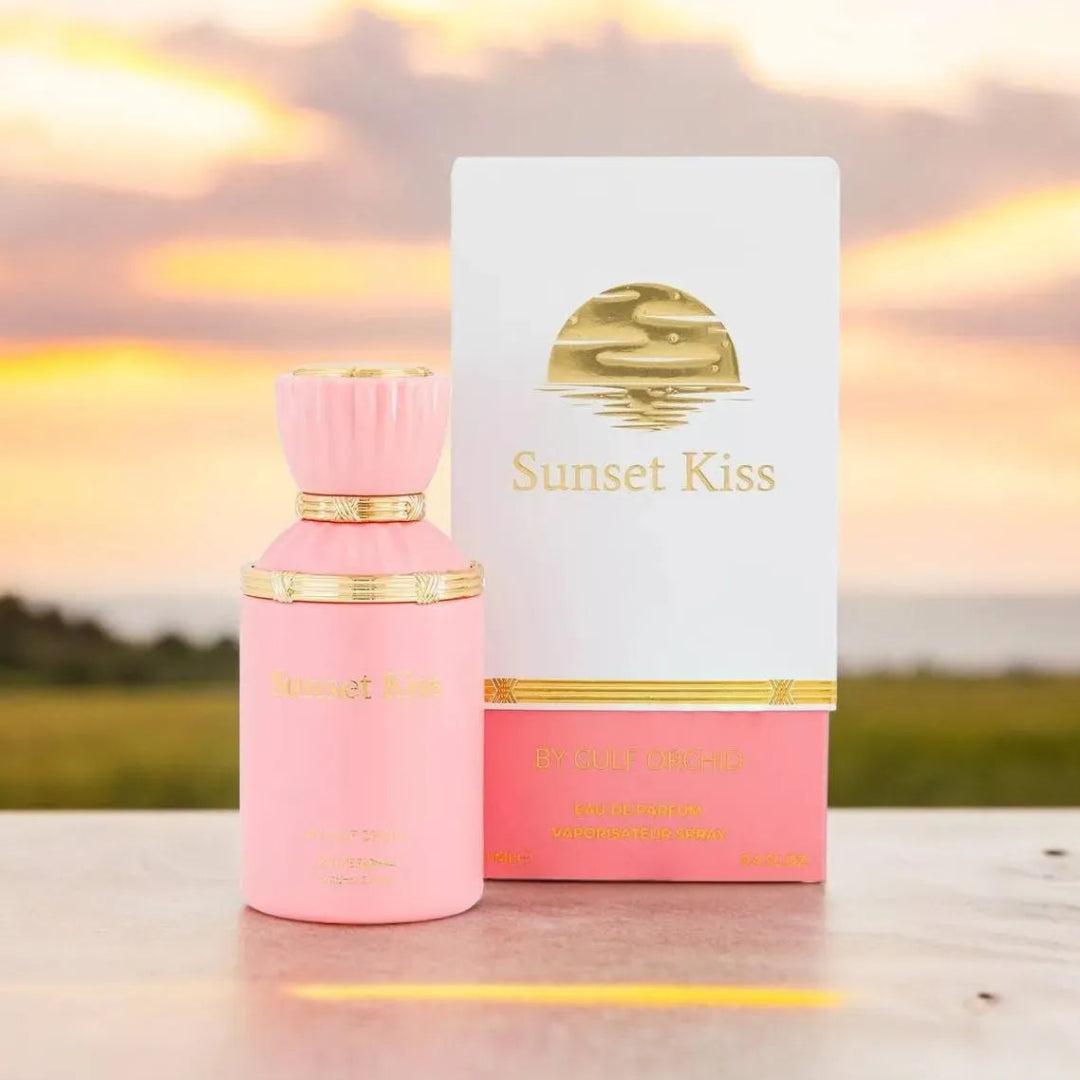 Pink 'Sunset Kiss' perfume bottle and packaging against a sunset background