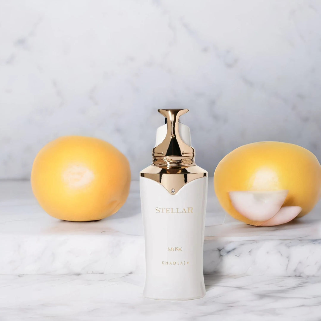 White skincare bottle with gold cap on a marble surface with two yellow fruits.