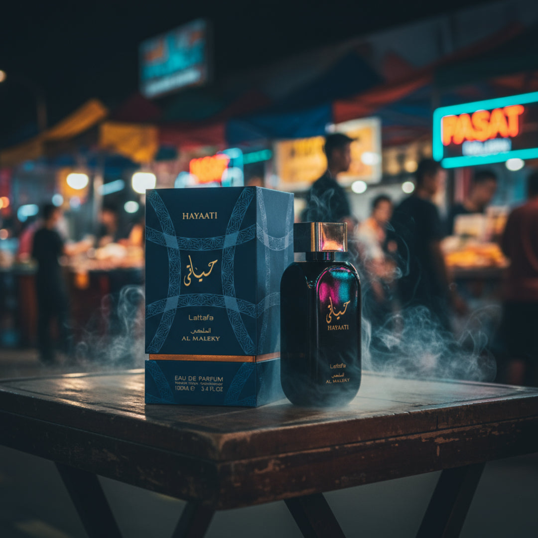 Hayaati Al Maleky at a Malaysian night market table with neon ripples and faint oud smoke; bottle and box clearly visible.