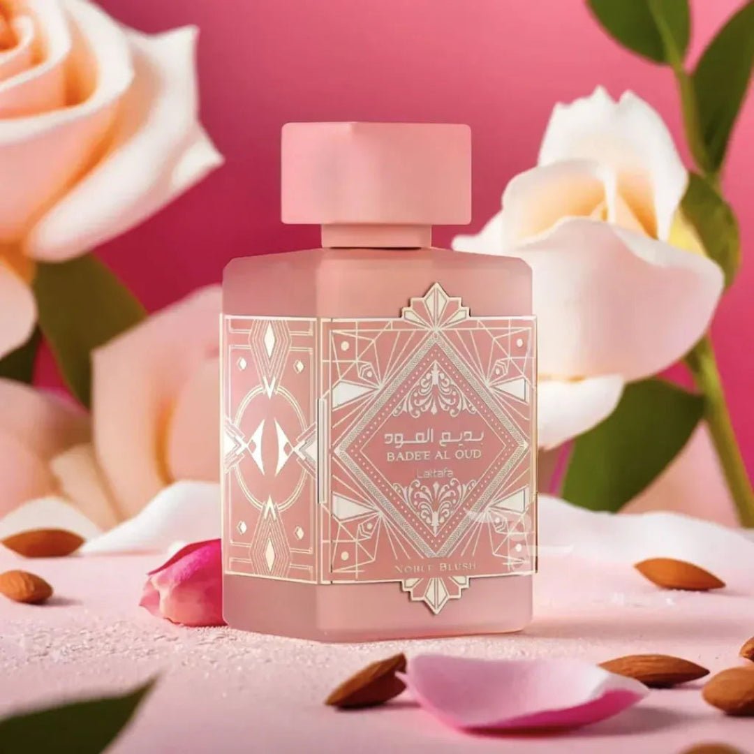 Pink perfume bottle with decorative label on a pink background with flowers and almonds.