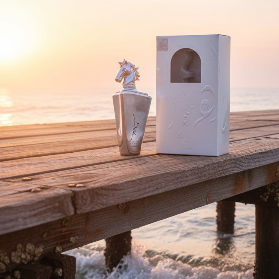 Lattafa Maahir Bottle &amp; box placed on weathered teak pier by the sea at golden hour; ocean waves gently lapping; salt mist visible; sunrise/early morning light.
