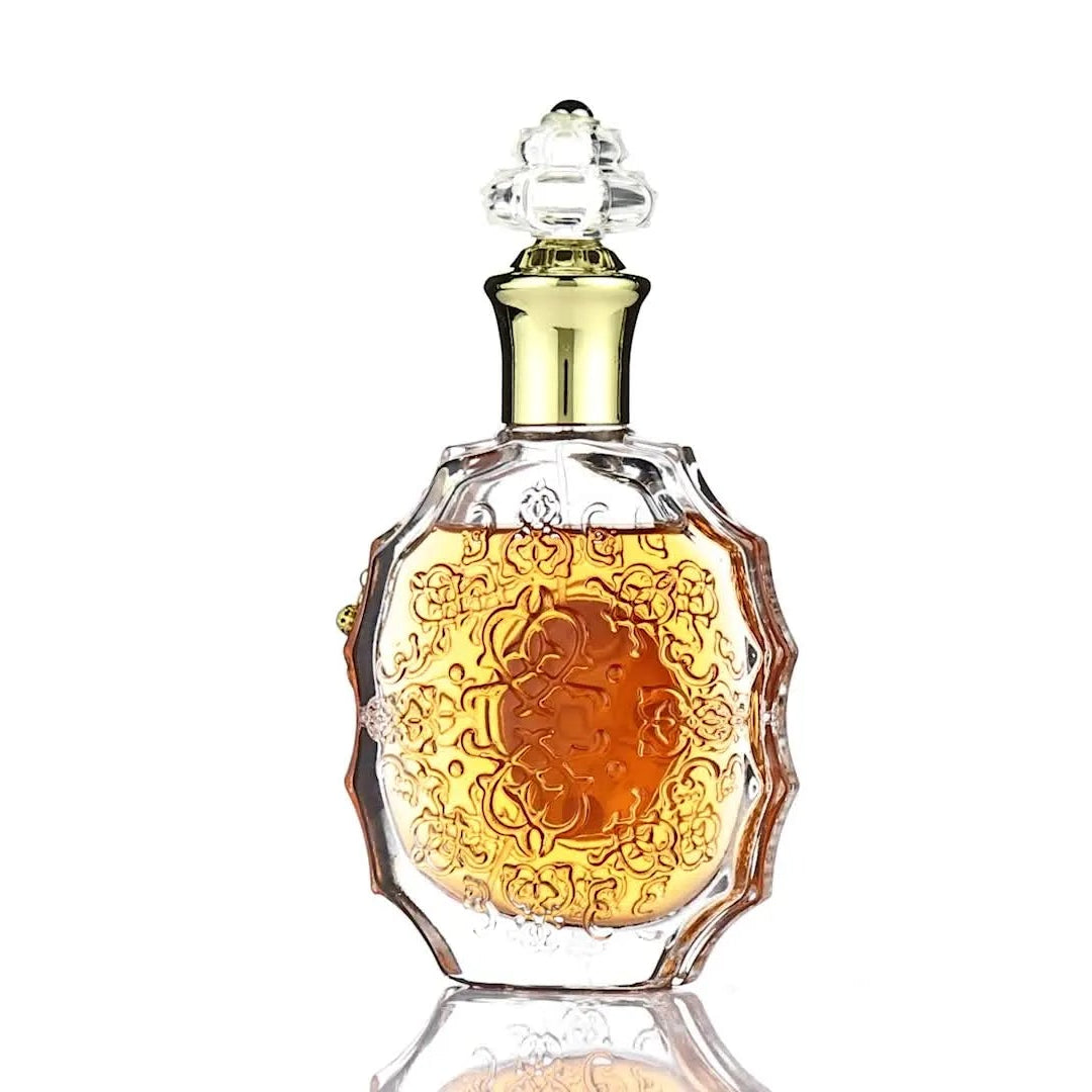 Perfume bottle with gold cap and intricate design on a white background