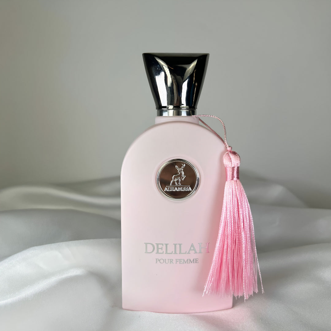 Pink perfume bottle with a tassel on a white fabric background