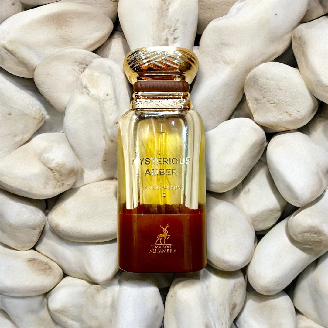 Perfume bottle labeled 'Mysterious Amber' on pebbles