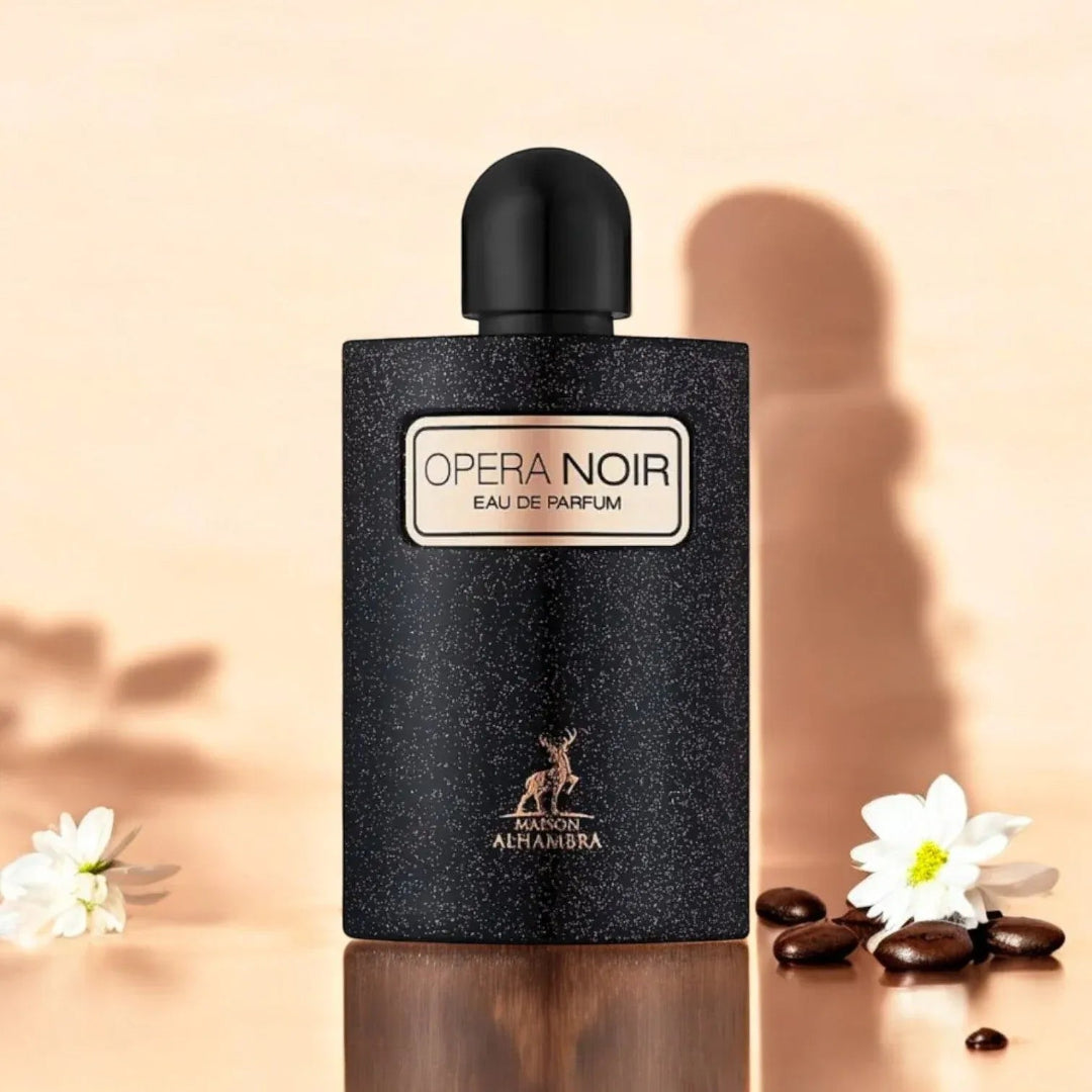 Black perfume bottle labeled 'Opera Noir' with flowers and stones on a beige background