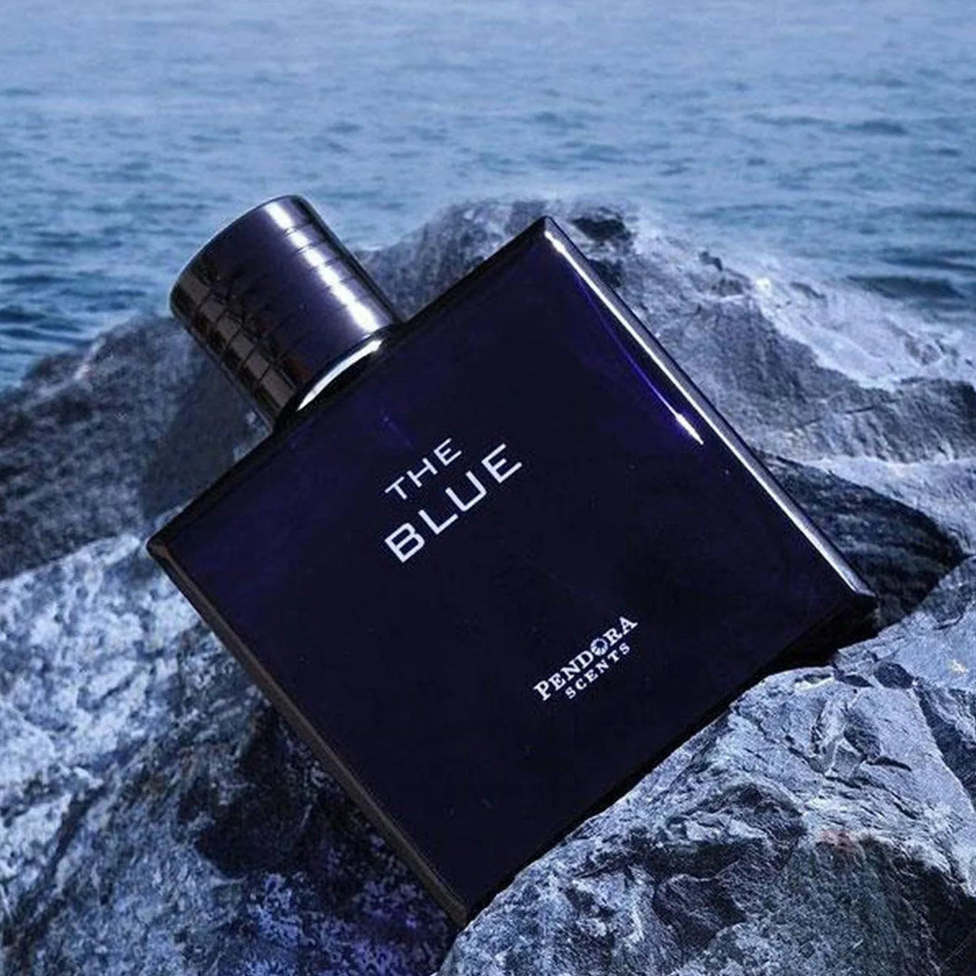 Perfume bottle labeled 'The Blue' by Fendriana on a rocky surface with ocean in the background