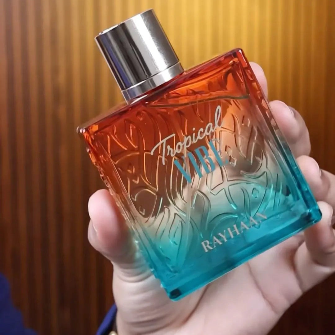Hand holding a bottle of 'Tropical Mist' by Ralph Lauren against a wooden background