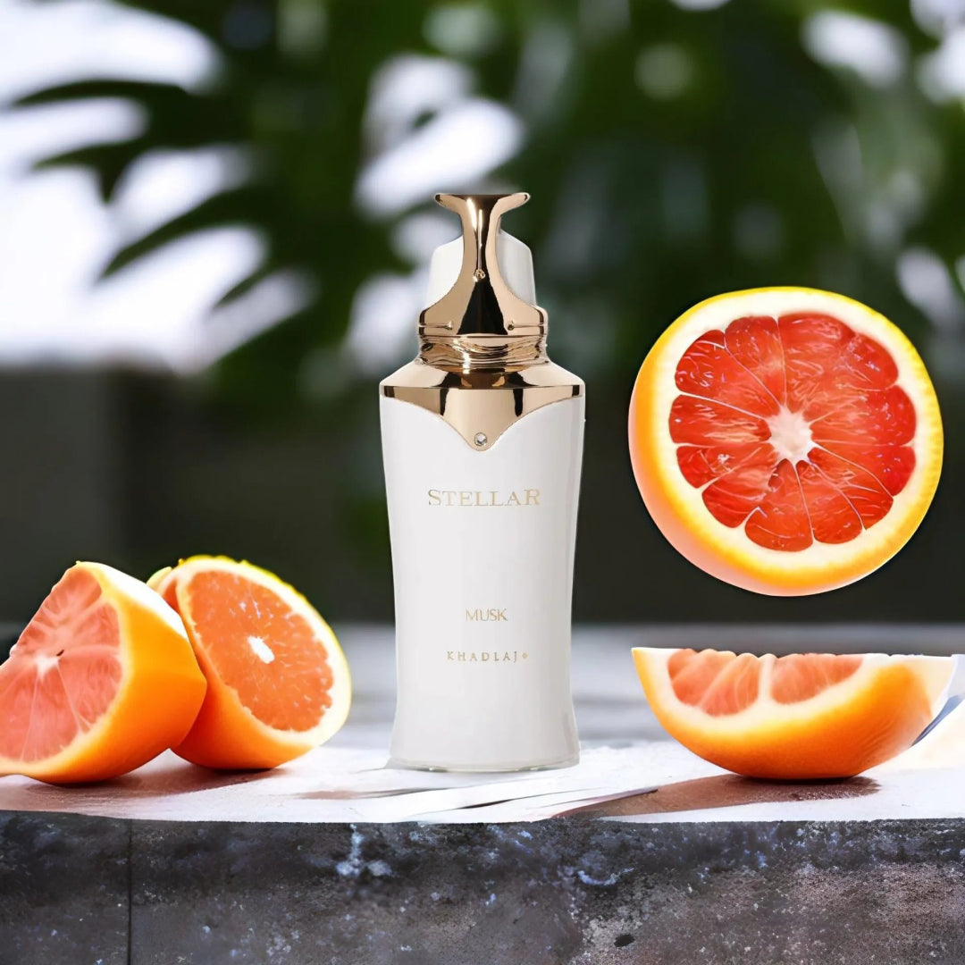 White bottle with gold cap labeled 'Stellar' next to sliced grapefruits on a dark surface.