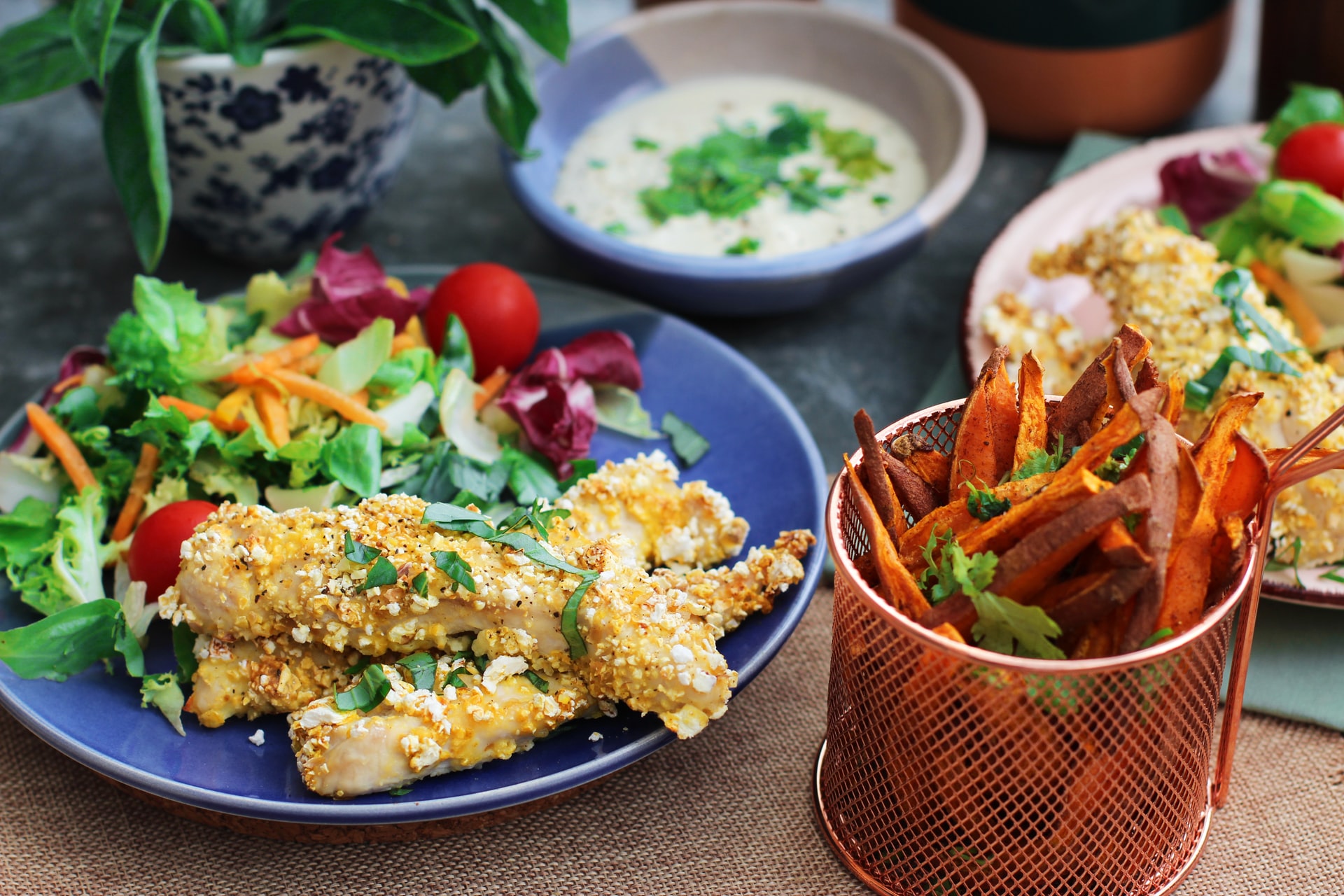 Popcorn coated chicken with a salad and sweet potato fries