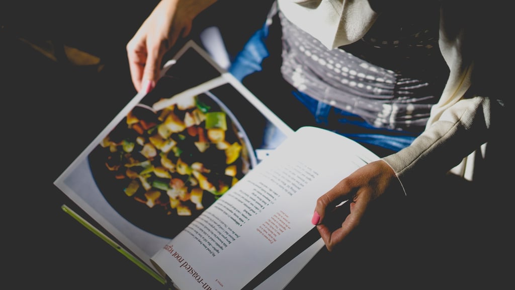 Person reading cookbook recipe