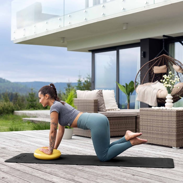 Balansoefening op genopt Hop-Sport balanskussen – activeert core en verbetert houding.