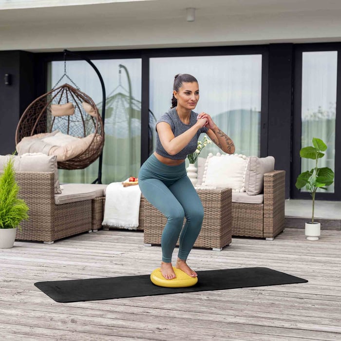 Kniebuiging op balanskussen – evenwichtstraining met Hop-Sport balans pad.