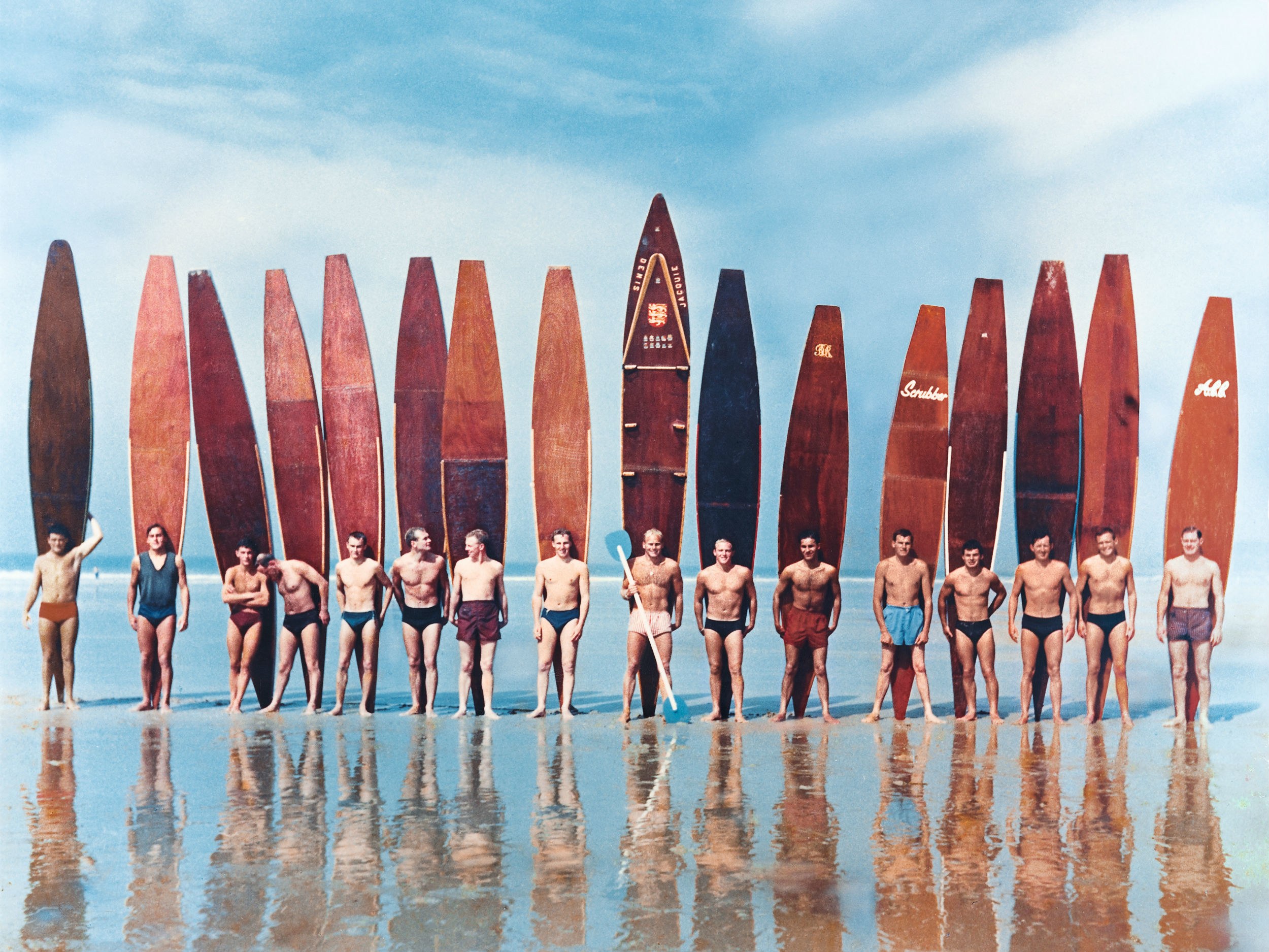 Surfers with boards lined on beach