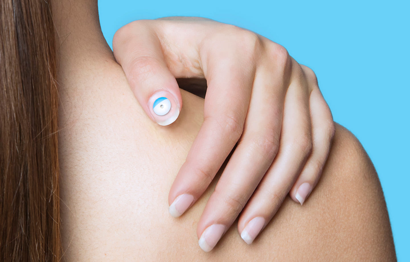 Woman's hand with light-colored nail polish and blue sticker on one nail