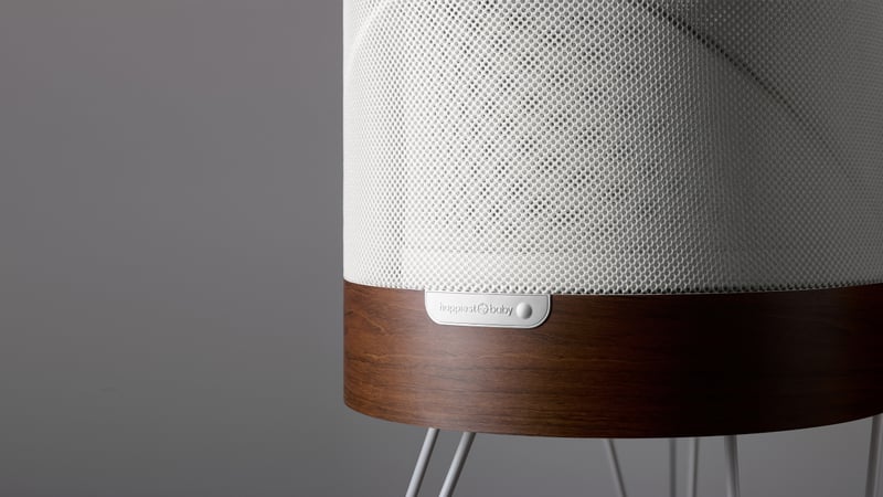 Gray speaker with wooden base and mesh fabric on neutral background