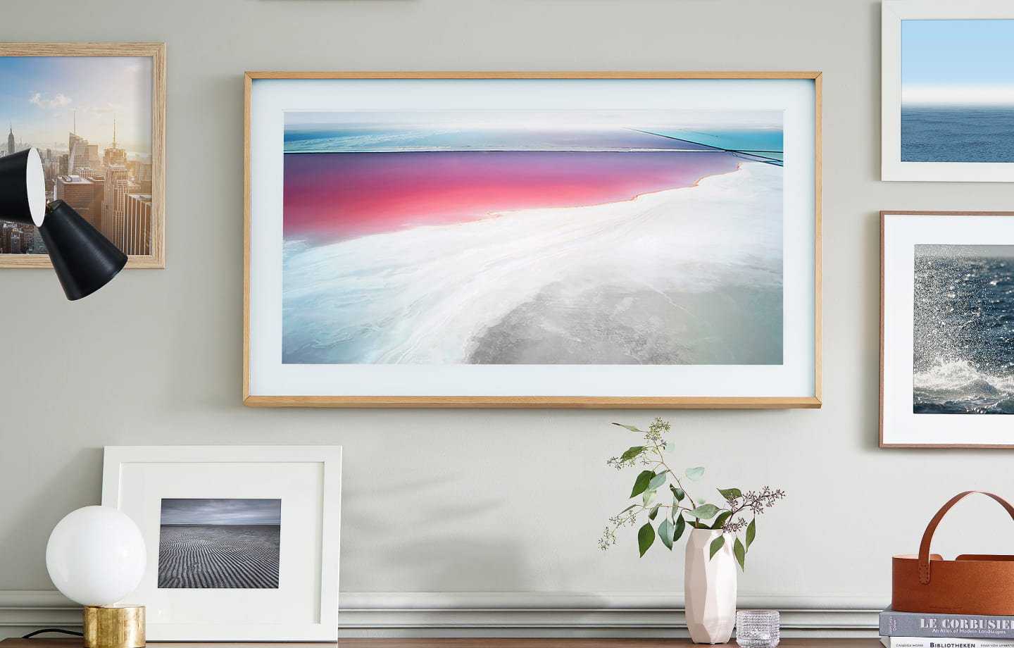 Samsung The Frame TV on a white wall displaying a sunset gradient artwork above a modern console in a living space.