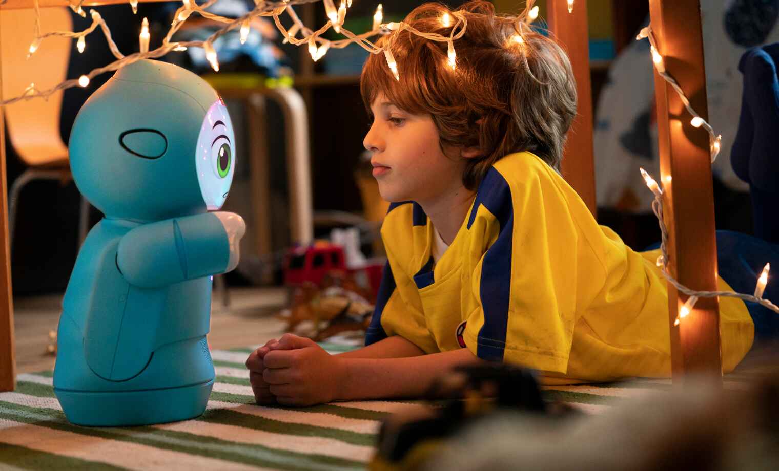 Child in yellow with blue robot toy