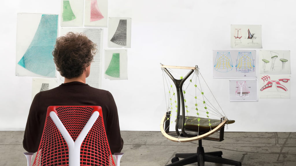 Worker in a red shirt at a Public Office Landscape standing desk with whiteboard panel and Sayl chair beside him.