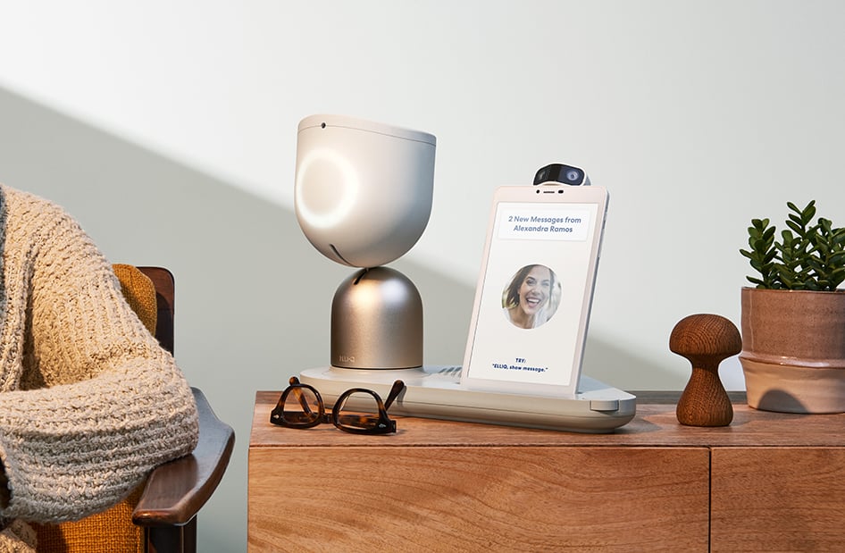 Person seated at a desk with a smart speaker and cardboard stand