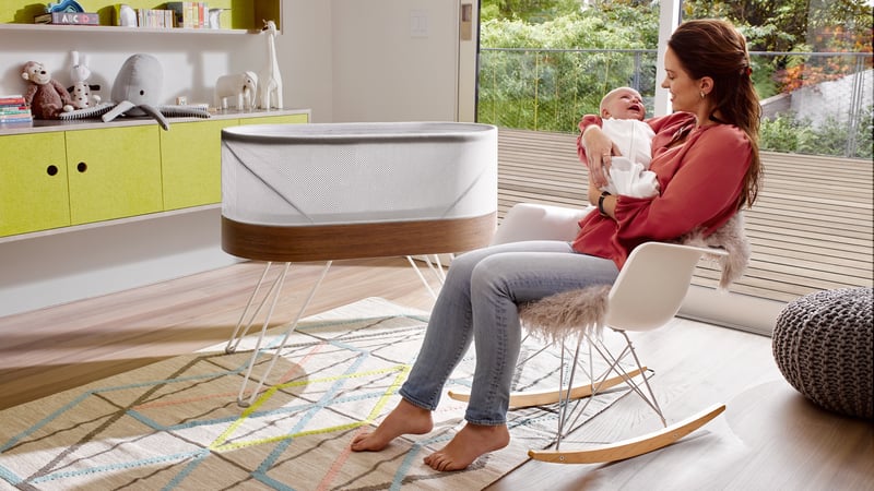 Woman holding baby in modern living room with green accent wall