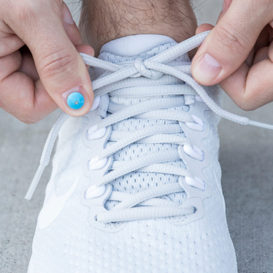 White sneakers with blue accents and mesh texture on a foot