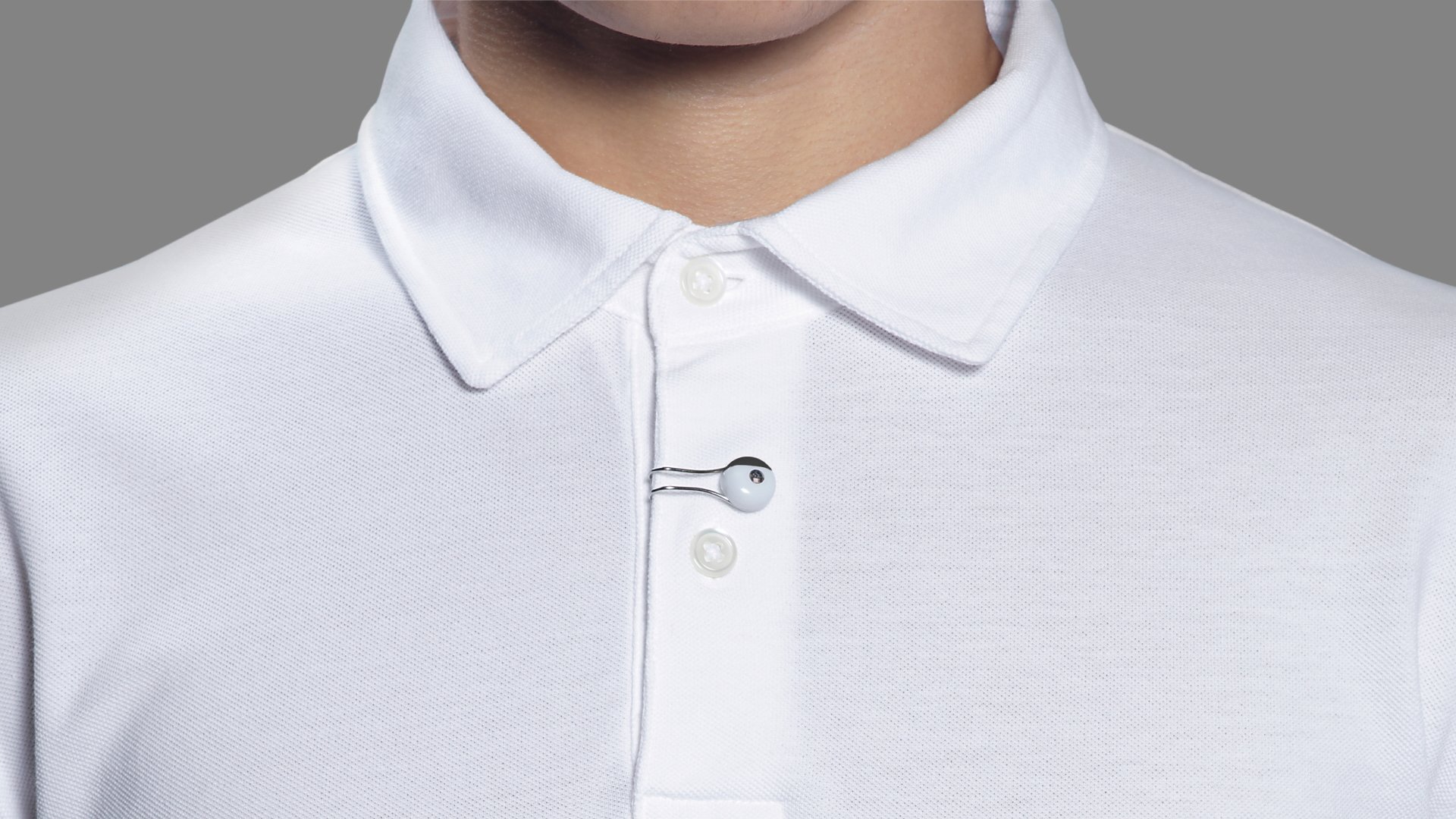 Man in a white collared shirt with a tie and collar pin