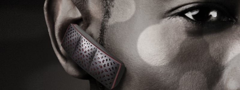 Close-up of a woman wearing the gray Jawbone Era Bluetooth earpiece with its sculpted hexagonal speaker pattern visible again