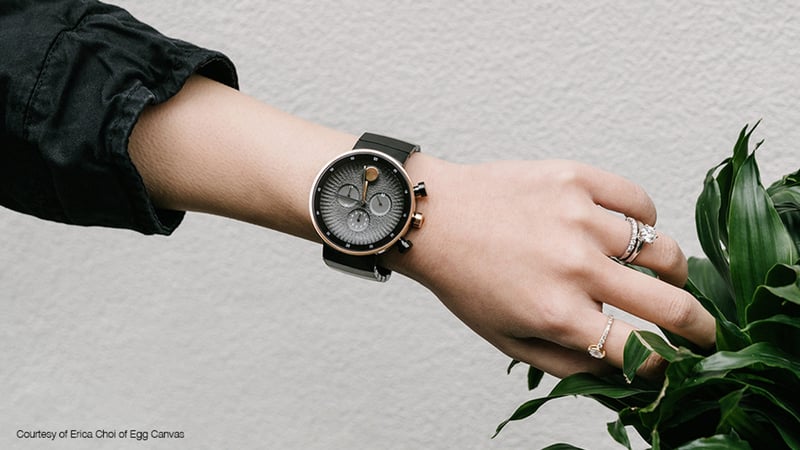 Hand holding rose gold smartwatch with black strap and digital face