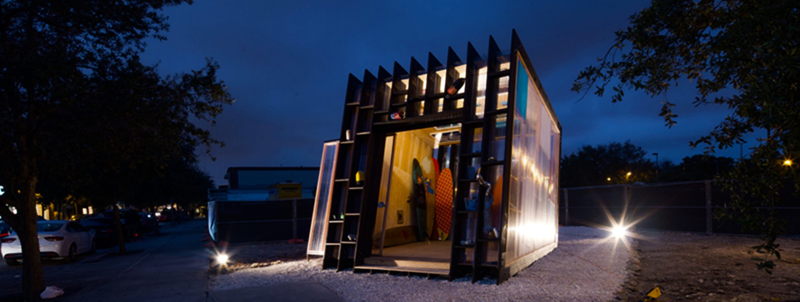 Modern metal or wood building with angular shapes, lit by spotlights at night