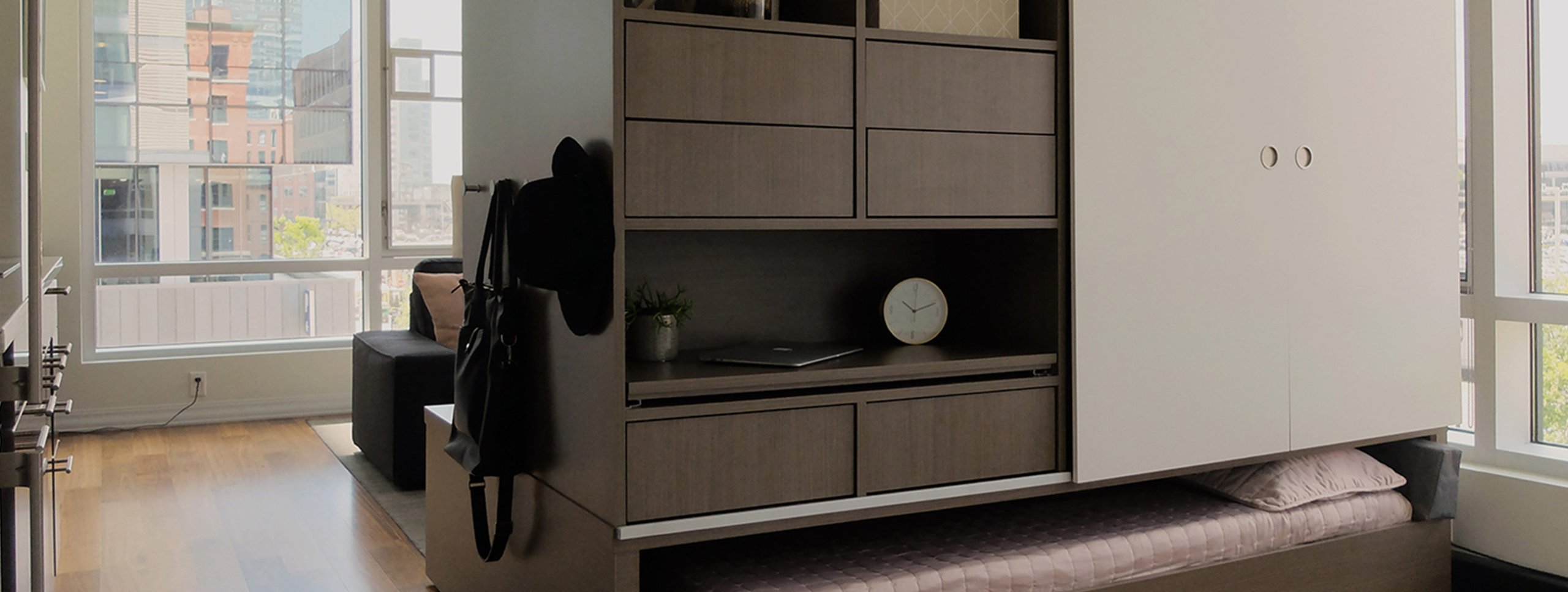 Ori transforming furniture studio apartment system with sliding storage wall pulled out to reveal Murphy bed and integrated w