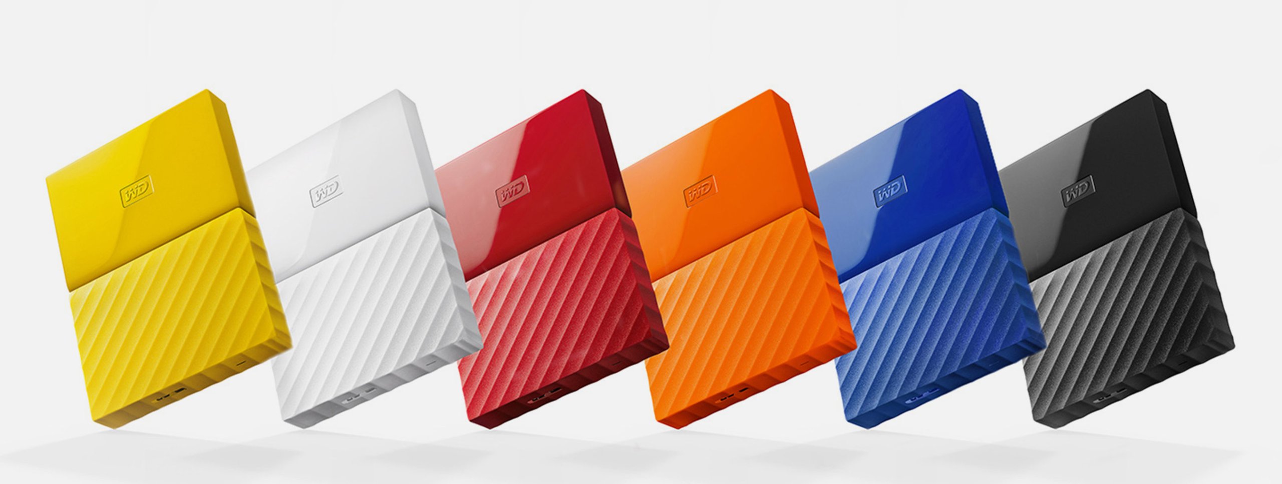 Western Digital My Passport portable hard drives in yellow, white, red, orange, blue and black with ridged textured base.