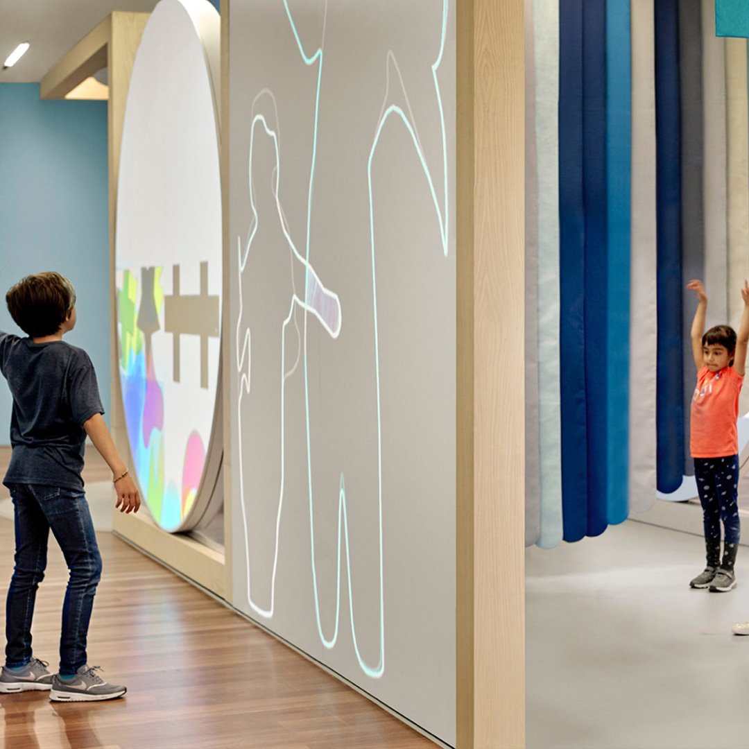 de Youngsters Studio: two children observing a large colorful wall display with patterns and designs