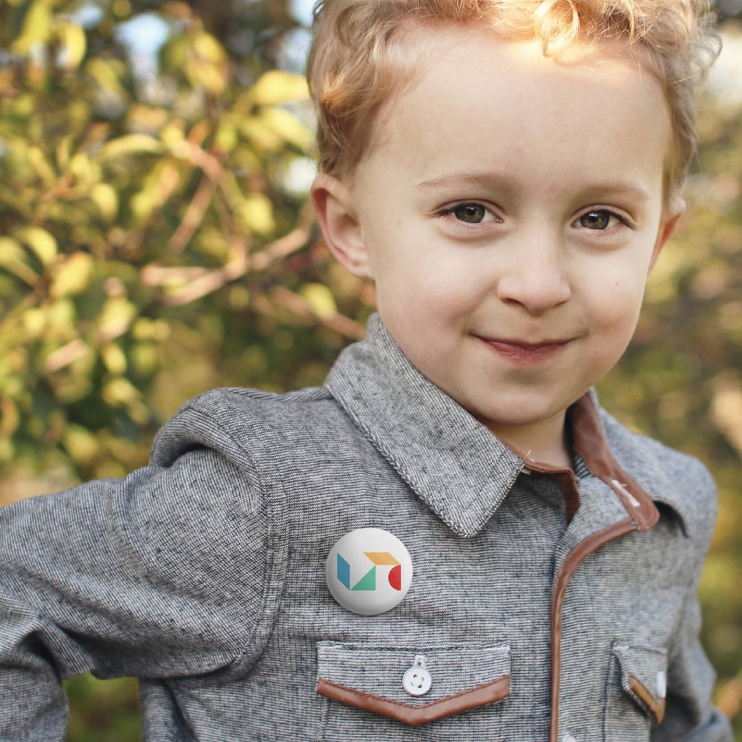 Young child with short blonde hair and a gray jacket smiling outdoors