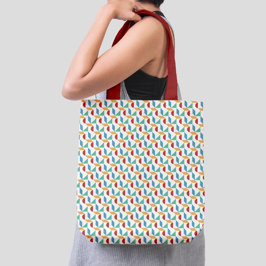 Woman with short dark hair and red strap top holds colorful tote bag