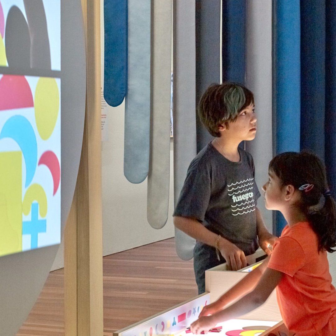 de Youngsters Studio: child and adult exploring an art gallery with colorful toys and artwork displayed on shelves