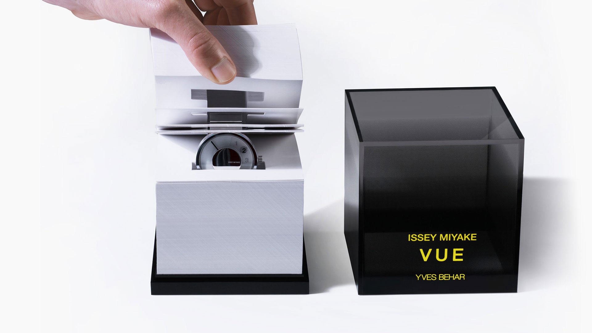 Issey Miyake VUE watch packaging by Yves Behar: white pop-up booklet displaying the watch beside a smoked acrylic cube box wi