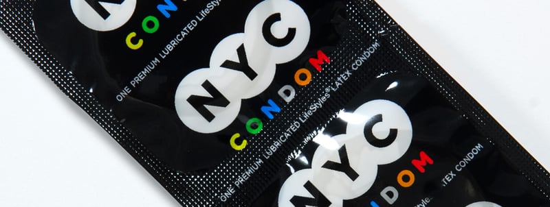 Black packages with NYC and CONDOM branding, colorful circular designs