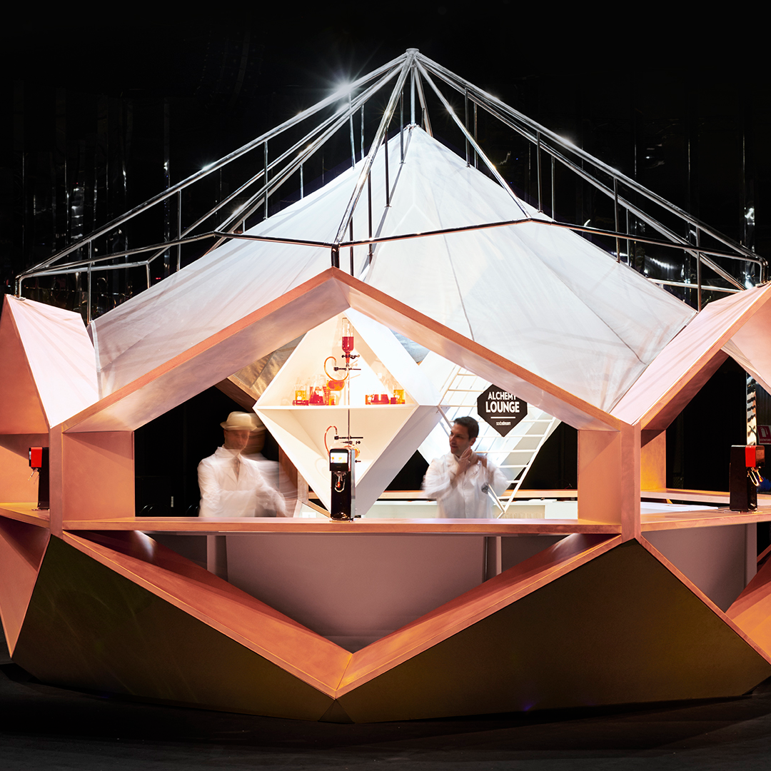 Modern event space with large triangular structure and pink-orange bar