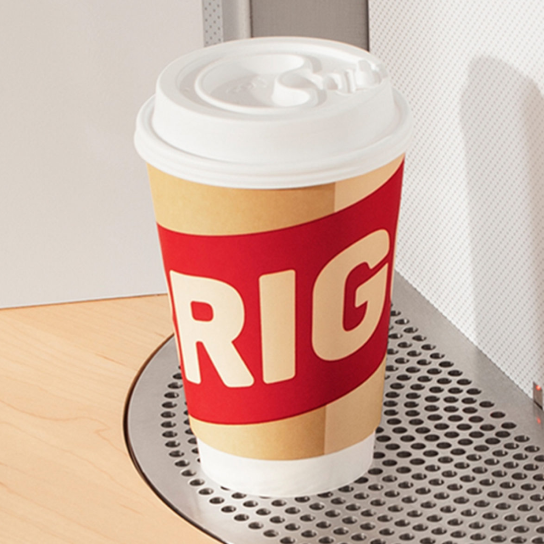 Red and white coffee cup on a metal surface next to a